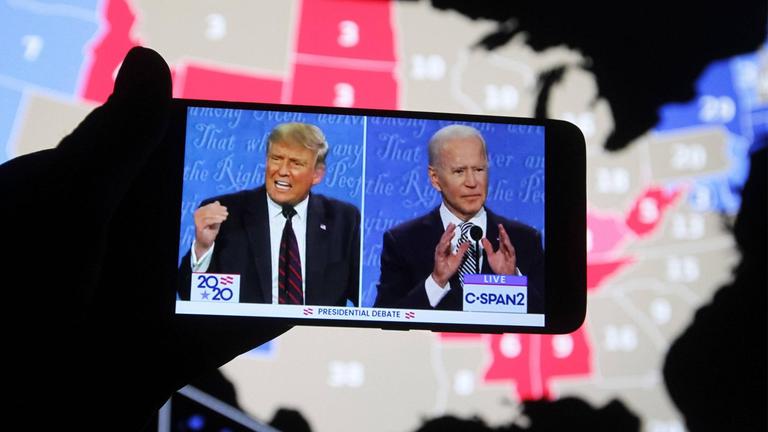 US-Präsident Donald Trump von den republikanern und sein Herausforderer, der frühere US-Vize-Präsident Joe Biden während der ersten TV-Debate auf einem Smartphone-Bildschirm. Im Hintergrund eine Karte der USA.