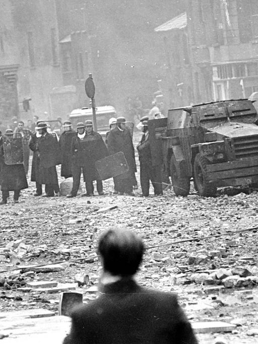 Polizisten stehen Demonstranten 1969 in einer zerstörten Szenerie im nordirischen Derry gegenüber
