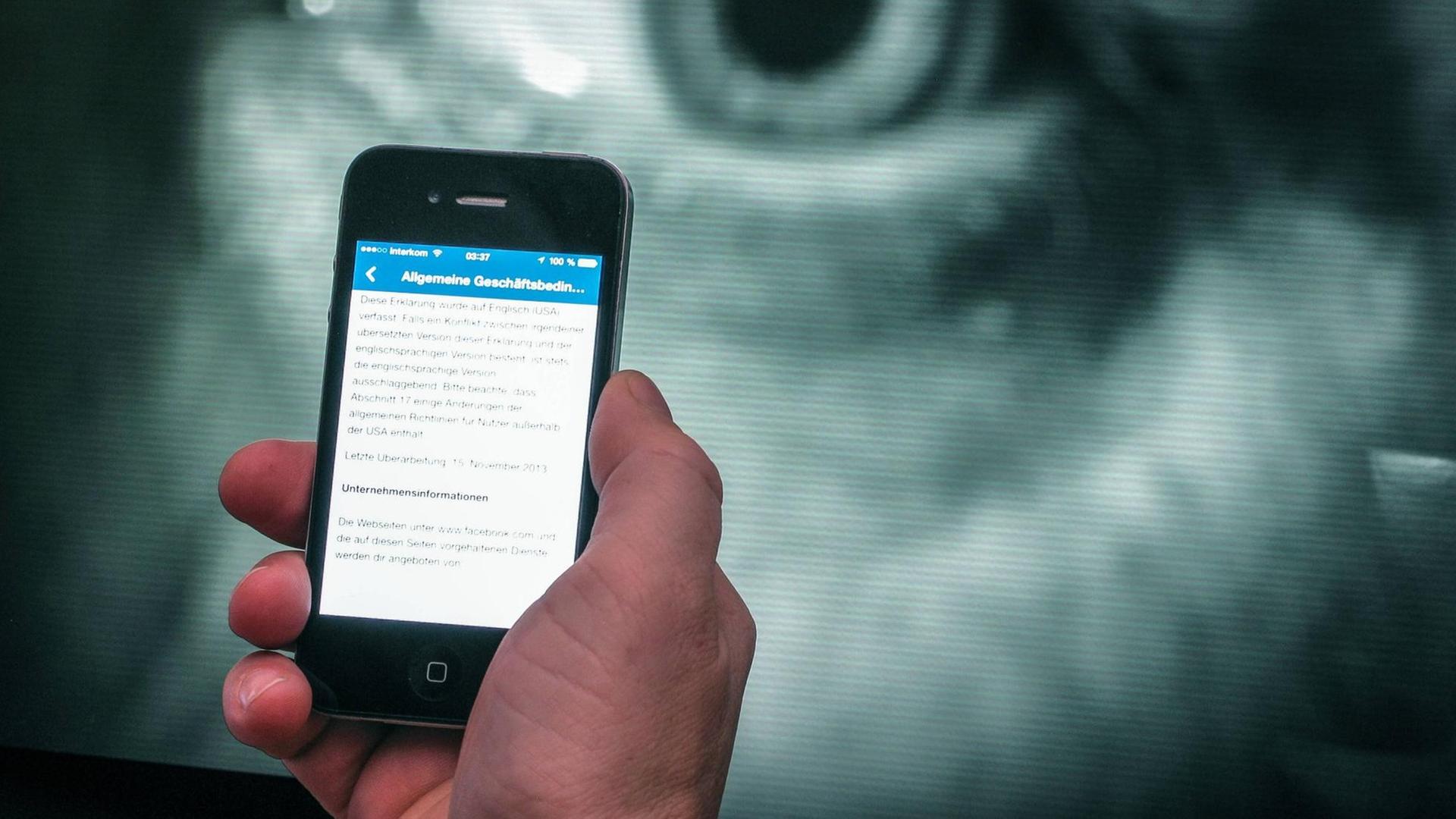 Ein Smartphone vor dem Bild eines großen Auges Ein Smartphone vor dem Bild eines großen Auges