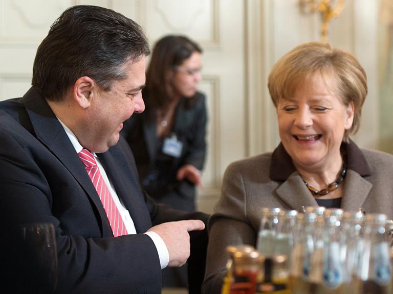 Bundeswirtschaftsminister Sigmar Gabriel (SPD) und Bundeskanzlerin Angela Merkel (CDU) lachen während einer Unterhaltung in Meseberg (Brandenburg) bei der Klausurtagung des Bundeskabinetts.