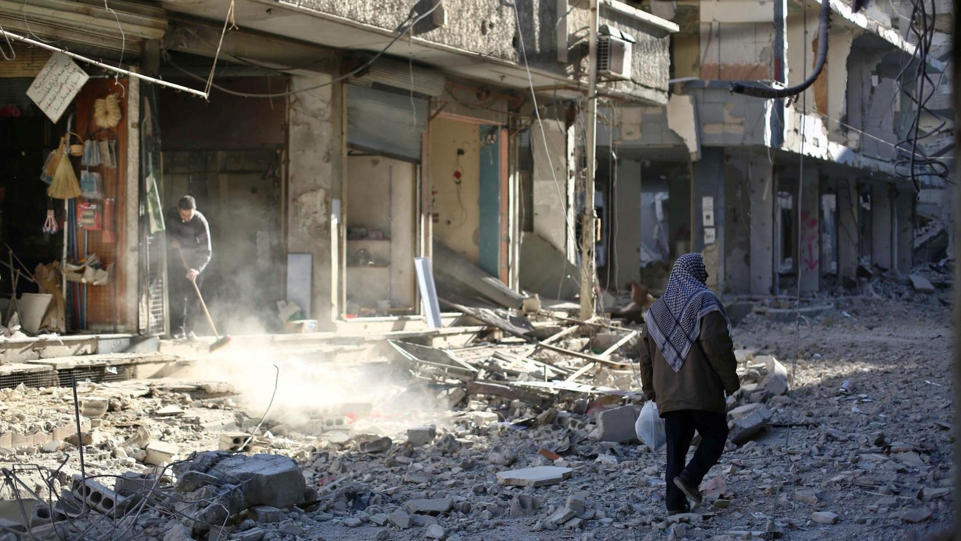 Ein Mann läuft durch eine Straße in der syrischen Stadt Duma, die voller Schutt ist. Ein Mann läuft durch eine Straße in der syrischen Stadt Duma, die voller Schutt ist.