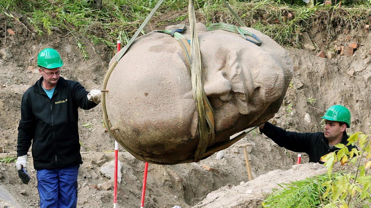 Arbeiter einer Spezialfirma sichern am 10.09.2015 in einem Waldstück am Müggelsee in Berlin den an einem Kran hängenden Kopf einer Lenin-Statue. Arbeiter einer Spezialfirma sichern am 10.09.2015 in einem Waldstück am Müggelsee in Berlin den an einem Kran hängenden Kopf einer Lenin-Statue.