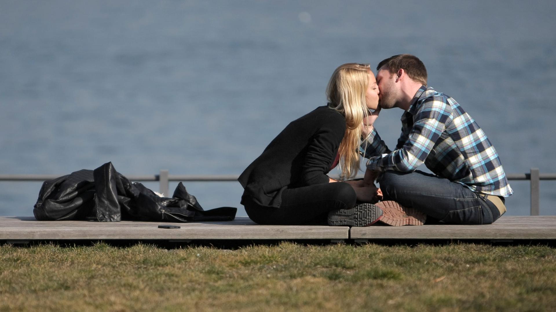 Ein verliebtes Paar genießt in Mainz am Rheinufer das sonnige Wetter und küssen sich auf der Uferpromenade. Ein verliebtes Paar genießt in Mainz am Rheinufer das sonnige Wetter und küssen sich auf der Uferpromenade.