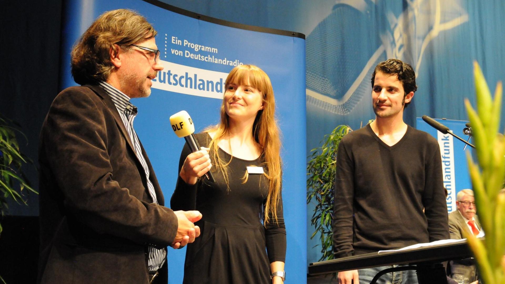 Ahmed Ahmed (r.) und Georg Radermacher mit Moderatorin Marina Schweizer auf der 5. Sportkonferenz im Deutschlandfunk Ahmed Ahmed (r.) und Georg Radermacher mit Moderatorin Marina Schweizer auf der 5. Sportkonferenz im Deutschlandfunk