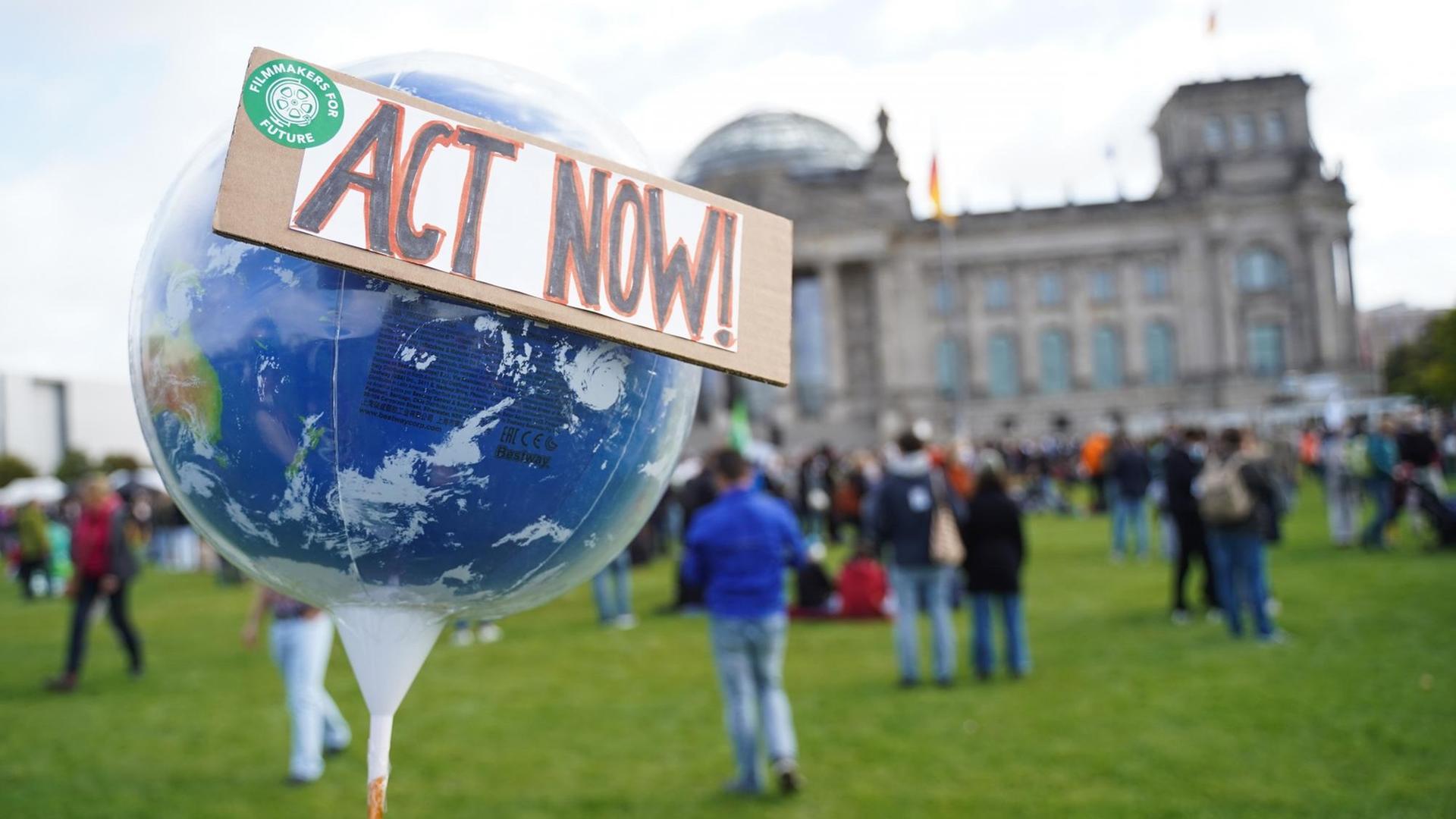 Ein Globus mit den Worten "Act now" ist bei einer Demonstration der Bewegung "Fridays for Future" vor dem Bundestag zu sehen. Kurz vor der Bundestagswahl finden deutschland- und weltweit Aktionen statt. Die Aktivisten fordern sozial gerechte und effektive Maßnahmen, um den globalen Temperaturanstieg auf 1,5 Grad Celsius zu begrenzen.