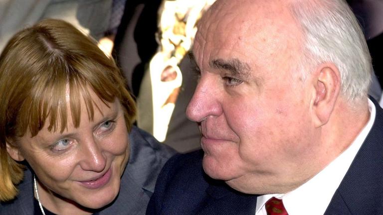 Die damalige CDU-Vorsitzende Angela Merkel sitzt neben Bundeskanzler Helmut Kohl und lächelt ihn an Die damalige CDU-Vorsitzende Angela Merkel sitzt neben Bundeskanzler Helmut Kohl und lächelt ihn an
