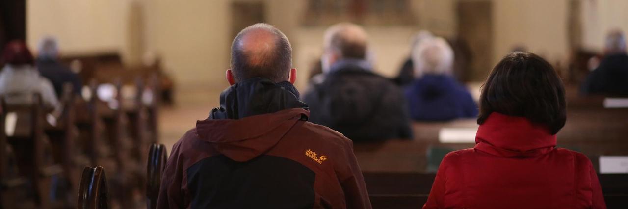 Besucher sitzen aufgrund der Corona-Pandemie mit Abstand zueinander in einer Kirche Besucher sitzen aufgrund der Corona-Pandemie mit Abstand zueinander in einer Kirche