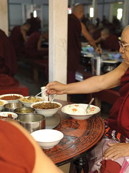 Buddhistische Mönche bei der Mönchsspeisung in einem Kloster in Myanmar