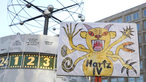 Ein Demonstrationsschild zeigt "Hartz IV" als Monster.