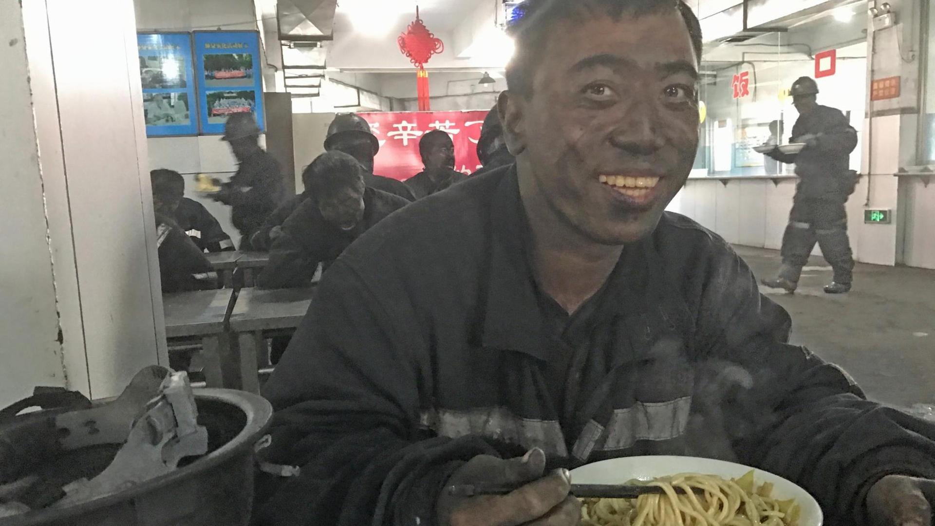 An einem Imbissstand im Kohlerevier von Yangquan sitzt ein Arbeiter mit schwarzem Kopf und isst Nudelsuppe. An einem Imbissstand im Kohlerevier von Yangquan sitzt ein Arbeiter mit schwarzem Kopf und isst Nudelsuppe.