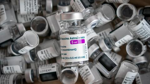 Eine leere Impfampulle der Firma AstraZeneca liegt auf leeren Ampullen der Firma Biontech/Pfizer (Comirnaty).