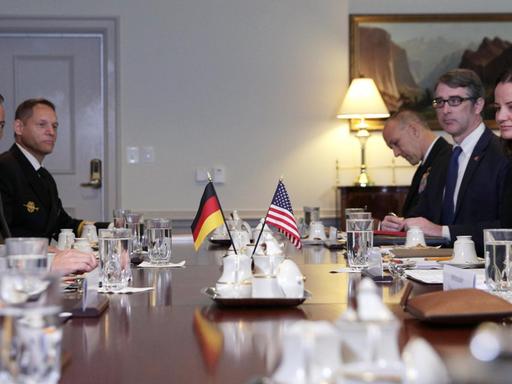 Annegret Kramp-Karrenbauer und Mark Esper sitzen sich an einem Tisch gegenüber, in der Mitte die beiden Flaggen.