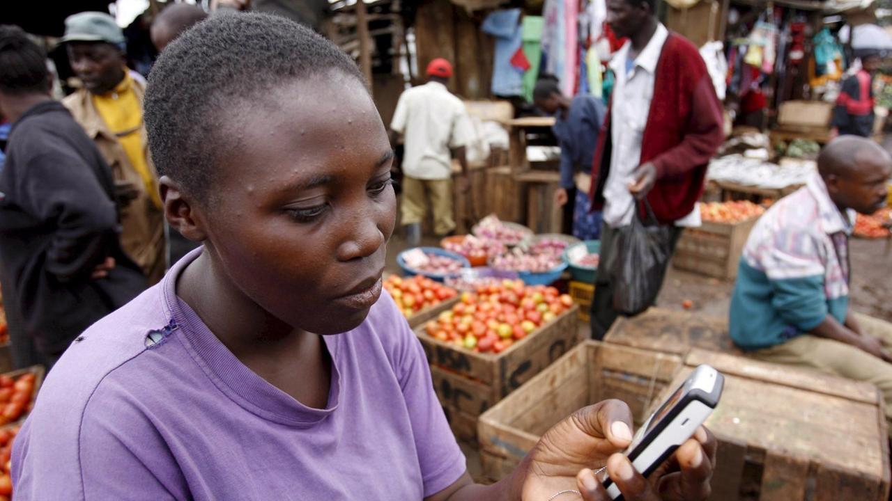 Eine Straßenhänderlin in Kenia verschickt mit ihrem Handy eine Textnachricht.
