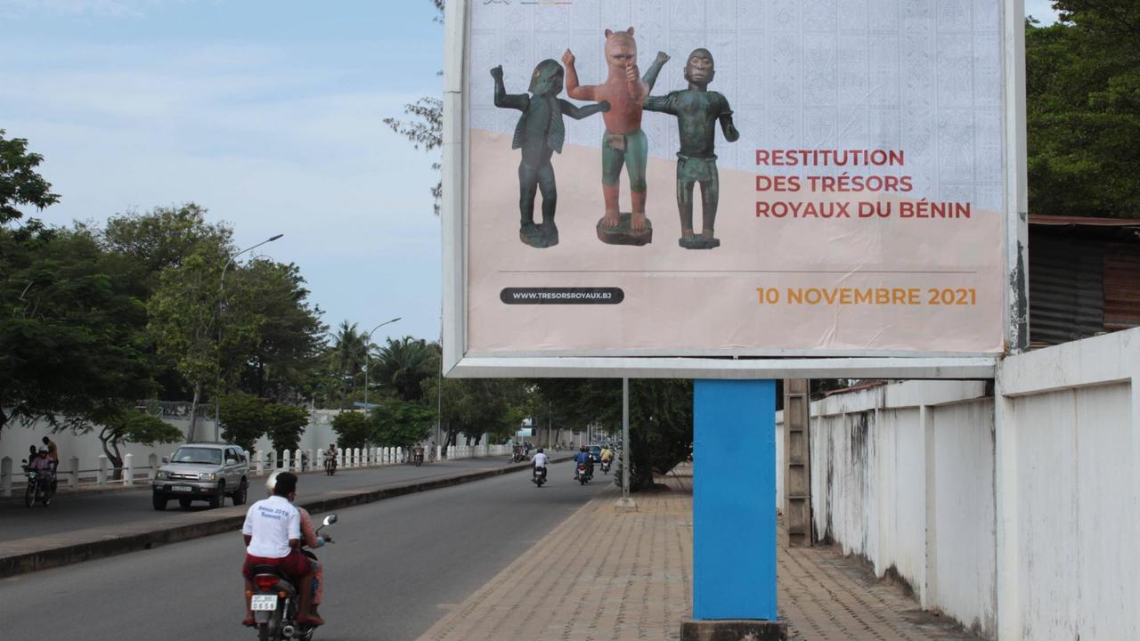 Plakat in Benins Hauptstadt Cotonou kündigt die Ankunft der von Frankreich zurückgegebenen Kunstwerke an, die während der Kolonialzeit im 19. Jahrhundert geraubt worden waren Plakat in Benins Hauptstadt Cotonou kündigt die Ankunft der von Frankreich zurückgegebenen Kunstwerke an, die während der Kolonialzeit im 19. Jahrhundert geraubt worden waren