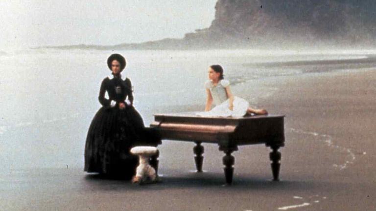 Eine Frau steht an einem Strand, neben ihr liegt ein Mädchen auf einem Piano. Eine Frau steht an einem Strand, neben ihr liegt ein Mädchen auf einem Piano.