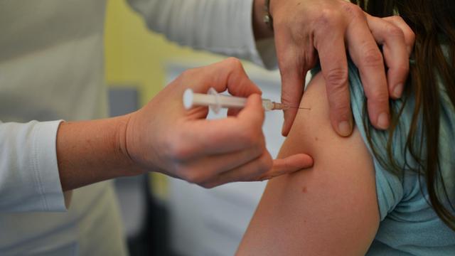 Eine Impfung wird in einen Oberarm gegeben