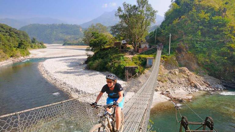 Eine Dame fährt auf einem Mountainbike über eine hängende Brücke. Eine Dame fährt auf einem Mountainbike über eine hängende Brücke.
