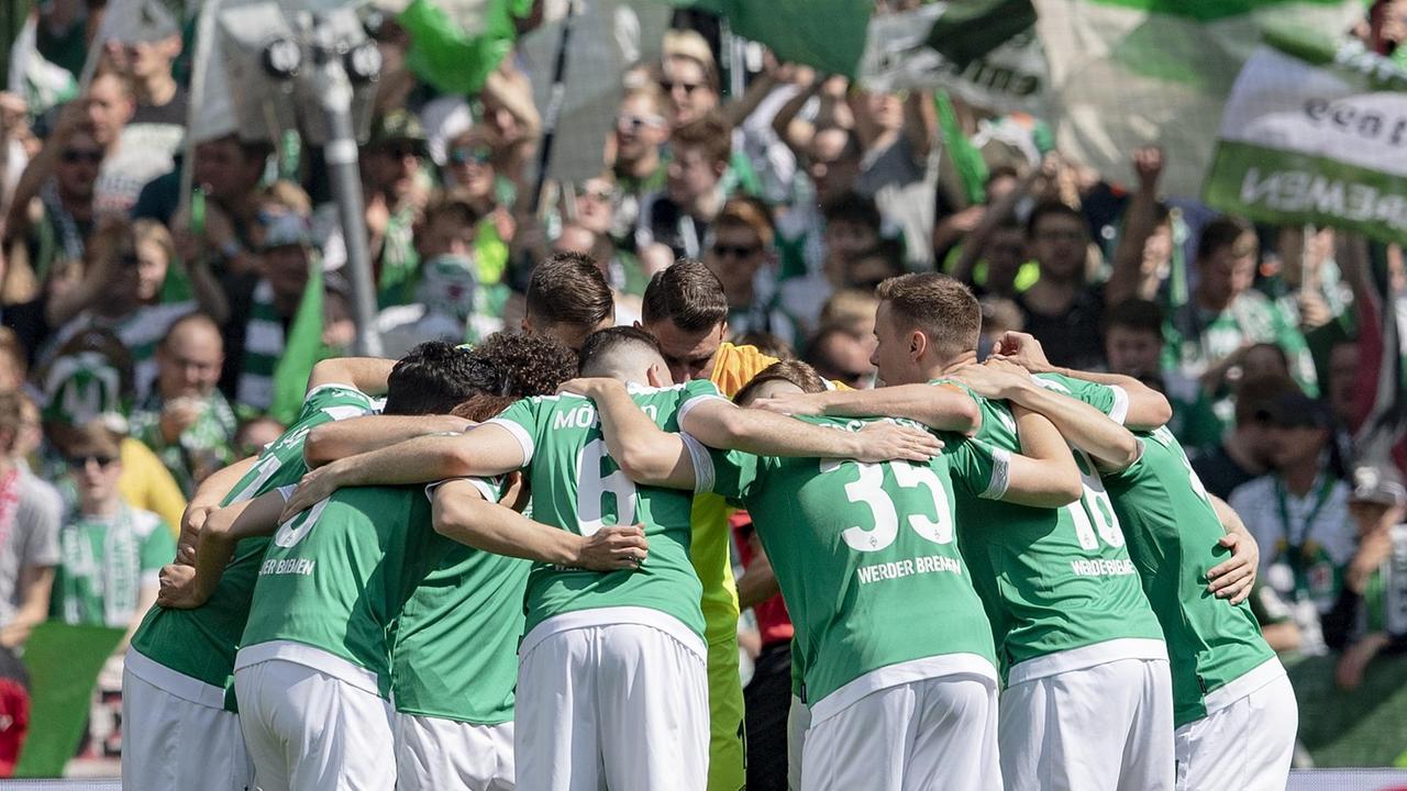 Die Bremer Spieler schwören sich vor dem Spiel vor der Tribüne der Bremer Fans ein, die Fahnen schwenken am am 18.05.2019 in Bremen Die Bremer Spieler schwören sich vor dem Spiel vor der Tribüne der Bremer Fans ein, die Fahnen schwenken am am 18.05.2019 in Bremen