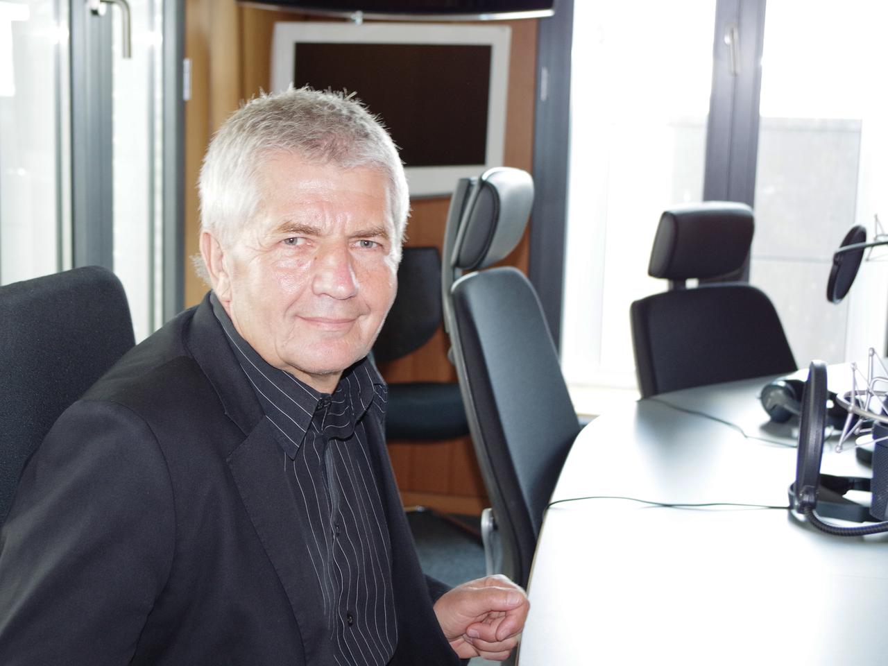 Roland Jahn sitzt an einem Tisch vor einem Mikrofon in einem Studio des Hauptstadtbüro des Deutschlandfunks und lächelt in die Kamera. Roland Jahn sitzt an einem Tisch vor einem Mikrofon in einem Studio des Hauptstadtbüro des Deutschlandfunks und lächelt in die Kamera.
