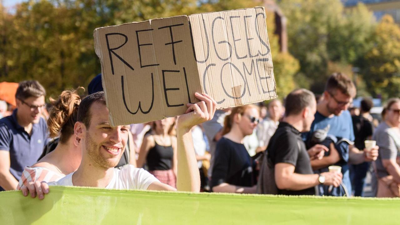 Ein Teilnehmer mit Schild Refugees welcome bei der Demonstration unter dem Motto Für eine offene Gesellschaft des Bündnis UNTEILBAR