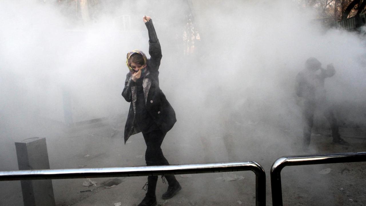 An Iranian woman raises her fist amid the smoke of tear gas at the University of Tehran during a protest driven by anger over economic problems, in the capital Tehran on December 30, 2017. Students protested in a third day of demonstrations sparked by anger over Iran's economic problems, videos on social media showed, but were outnumbered by counter-demonstrators. / AFP PHOTO / STR An Iranian woman raises her fist amid the smoke of tear gas at the University of Tehran during a protest driven by anger over economic problems, in the capital Tehran on December 30, 2017. Students protested in a third day of demonstrations sparked by anger over Iran's economic problems, videos on social media showed, but were outnumbered by counter-demonstrators. / AFP PHOTO / STR
