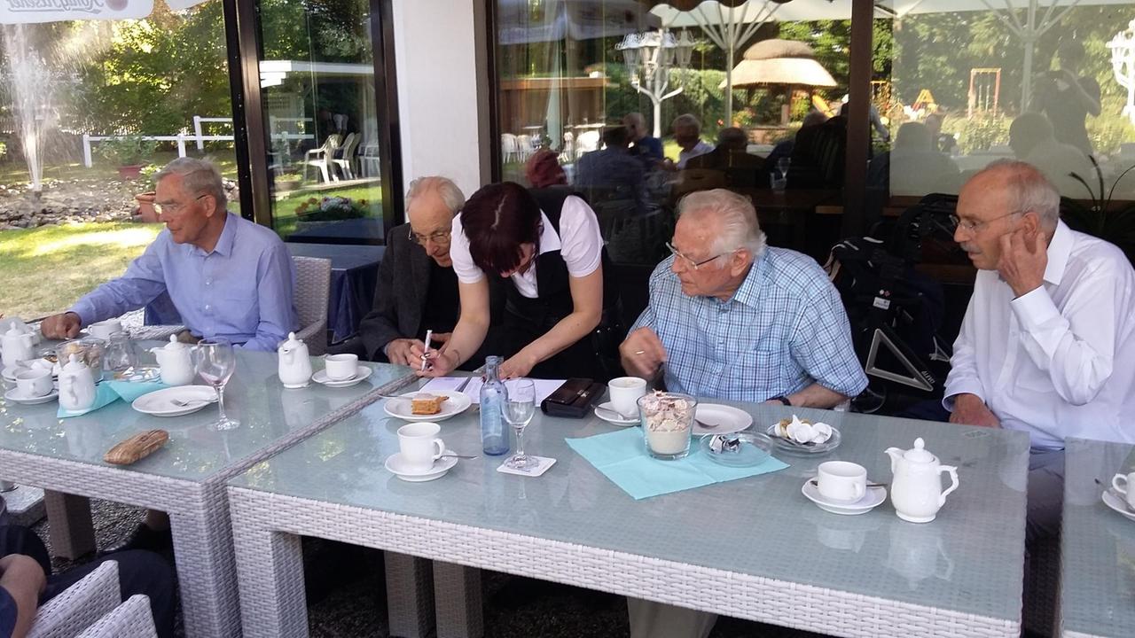 Im Restaurant mehrere alte Herren, die bezahlen bei der Bedienung Im Restaurant mehrere alte Herren, die bezahlen bei der Bedienung