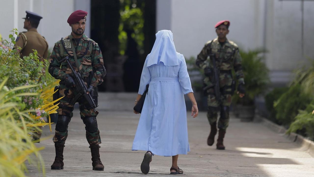 Nach den Anschlägen mit 258 Toten in Sri Lanka ist in der Hauptstadt Colombo erstmals wieder die katholische Sonntagsmesse gefeiert worden. Das Bild zeigt Soldaten, die eine Maschinenpistolen eine Kirche bewachen.