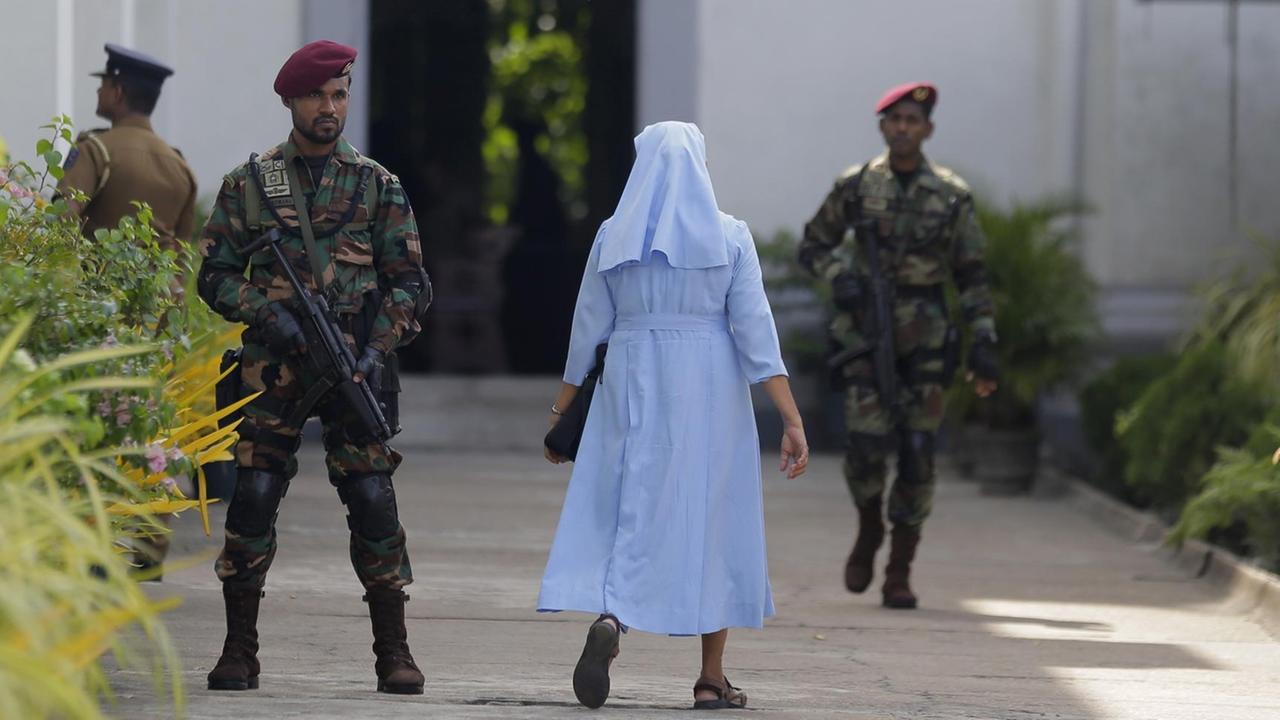 Nach den Anschlägen mit 258 Toten in Sri Lanka ist in der Hauptstadt Colombo erstmals wieder die katholische Sonntagsmesse gefeiert worden. Das Bild zeigt Soldaten, die eine Maschinenpistolen eine Kirche bewachen. Nach den Anschlägen mit 258 Toten in Sri Lanka ist in der Hauptstadt Colombo erstmals wieder die katholische Sonntagsmesse gefeiert worden. Das Bild zeigt Soldaten, die eine Maschinenpistolen eine Kirche bewachen.