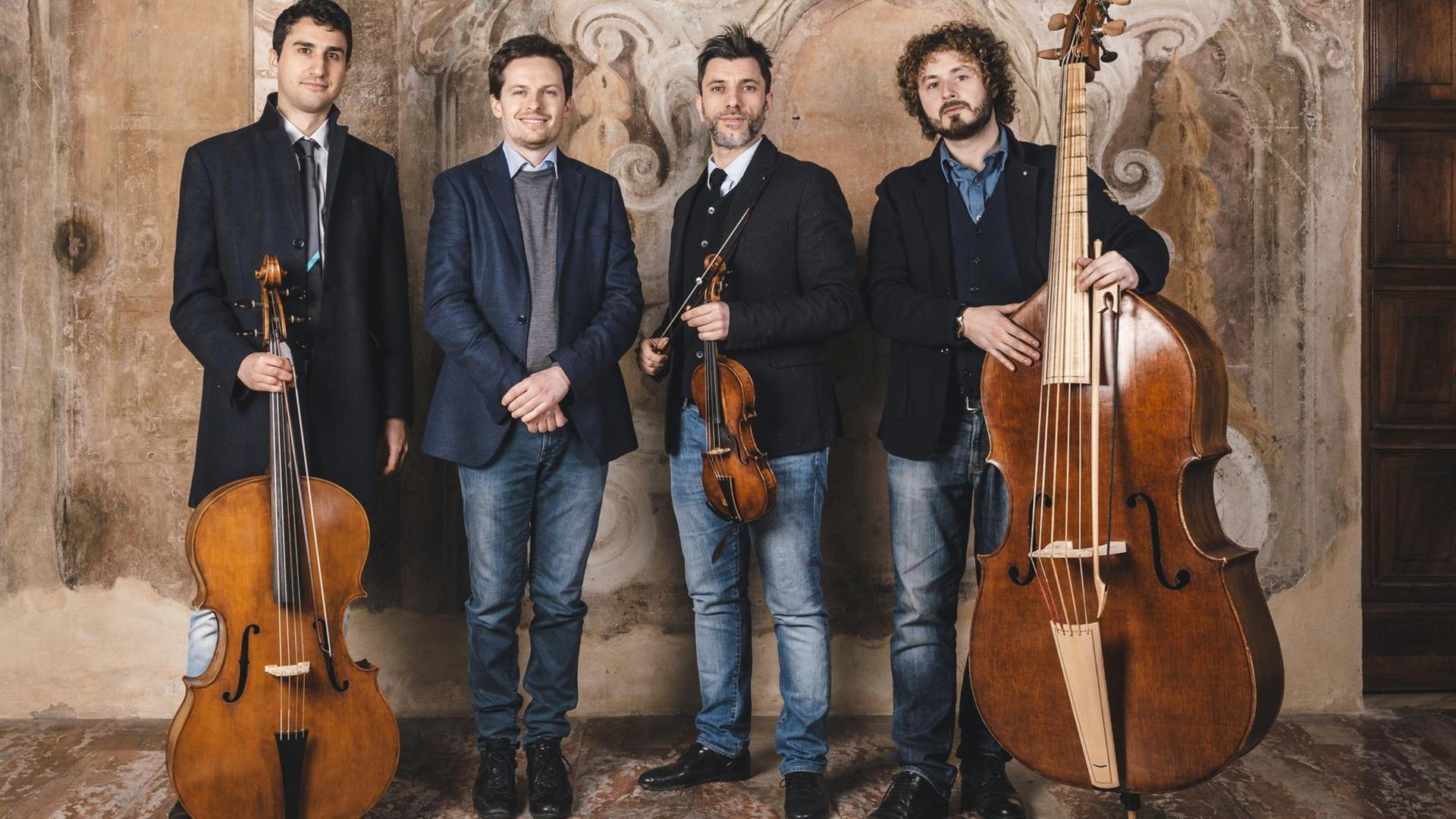 Das Quartetto Valvitelli mit dem Geiger Gian Andrea Guerra und Instrumenten vor einer verzierten Steinwand Das Quartetto Valvitelli mit dem Geiger Gian Andrea Guerra und Instrumenten vor einer verzierten Steinwand