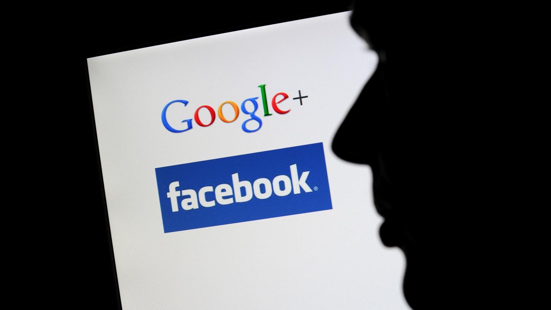 Die Silhouette eines Mannes zeichnet sich vor einem Computerbildschirm mit den Logos von Google+ und Facebook ab. Die Silhouette eines Mannes zeichnet sich vor einem Computerbildschirm mit den Logos von Google+ und Facebook ab.