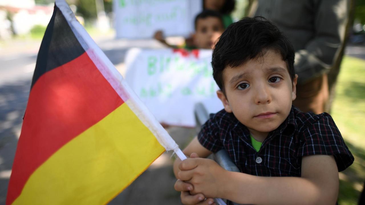 Der dreijährige Flüchtling aus Syrien, Tayem Mansor Alshalah, und andere protestiert am 12.05.2016 in Düsseldorf (Nordrhein-Westfalen) mit der deutschen Flagge in der Hand gegen ihre Unterbringung in einer Traglufthalle.