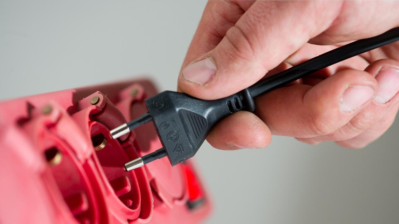 Ein Mann steckt in Berlin einen Stecker in eine Steckerleiste. Ein Mann steckt in Berlin einen Stecker in eine Steckerleiste.