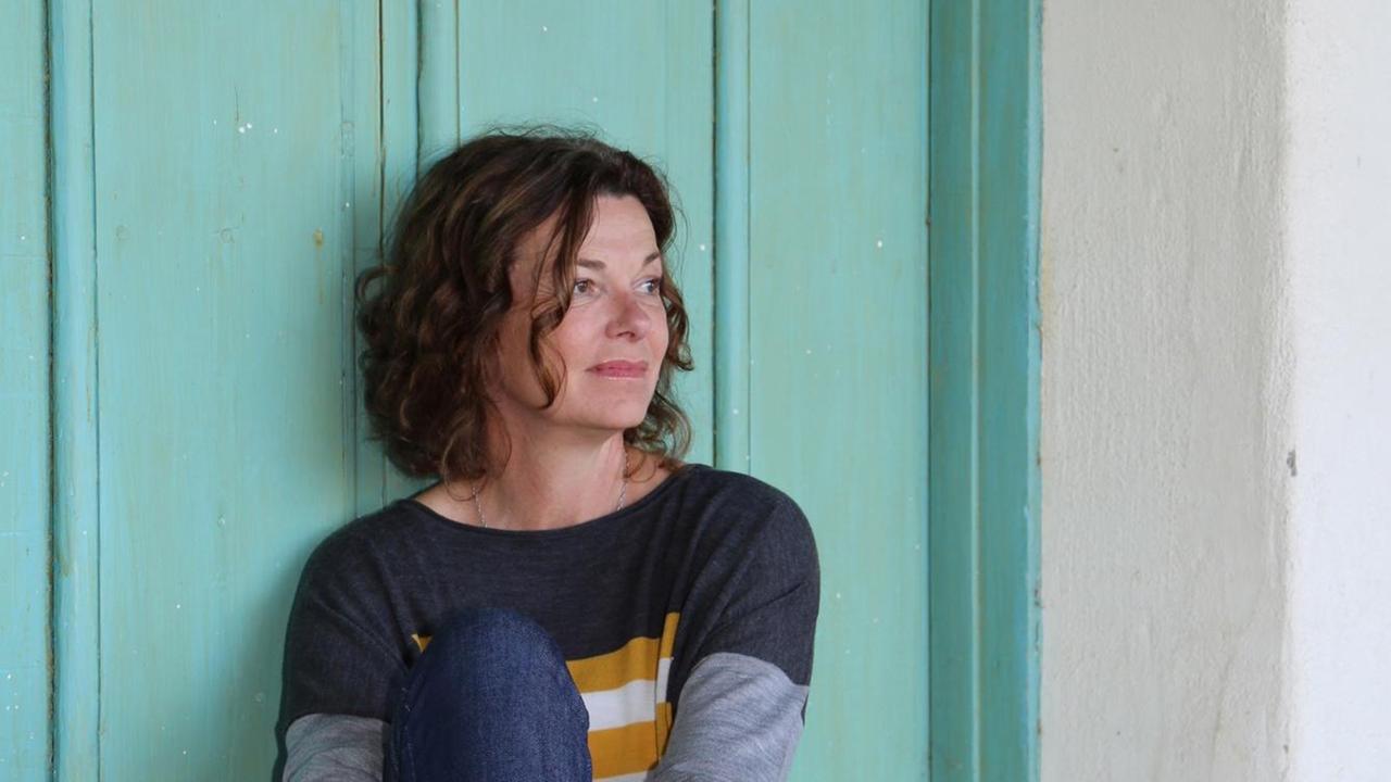 Die Schweizer Schriftstellerin Milena Moser vor einer tuerkisen Wand sitzend. Die Schweizer Schriftstellerin Milena Moser vor einer tuerkisen Wand sitzend.