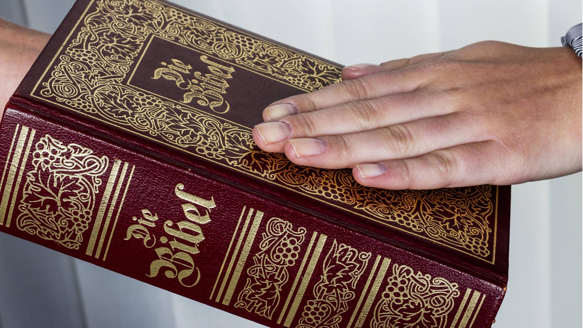 Ein Mann legt bei einem Schwur die Hand auf die Bibel.