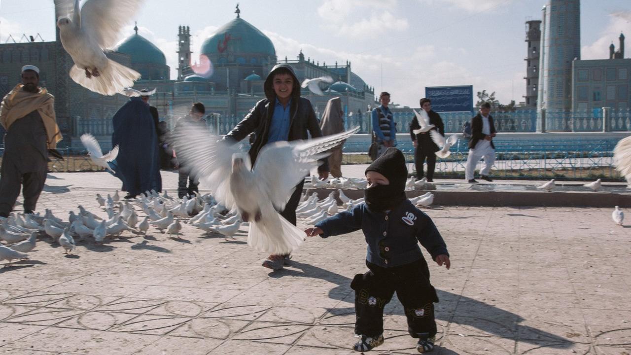 Kinder und Erwachsene mit auffliegenden weißen Tauben in Afghanistan