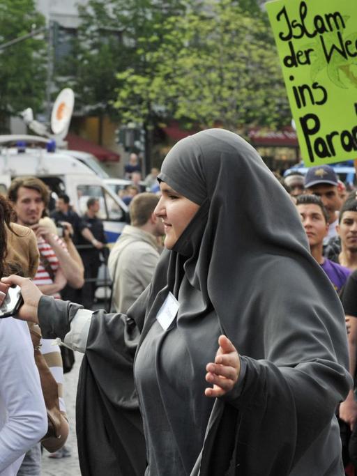 Eine Frau trennt Teilnehmer einer islamistischen Demonstration am Mittwoch (20.04.2011) in der Innenstadt von Frankfurt am Main nach Geschlechtern. Der vielfach als islamistisch eingestufte salafistische Prediger Vogel hatte zu einer Demonstration unter dem Titel "Islam - die missverstandene Religion !" aufgerufen.