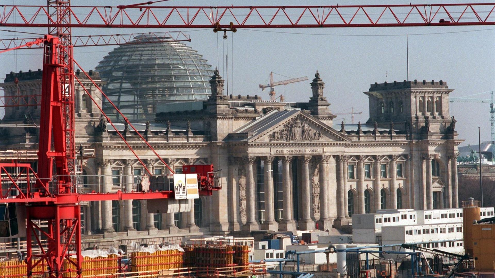 Das Reichstagsgebäude als Baustelle. Kräne und Baucontainer stehen vor dem Gebäude.