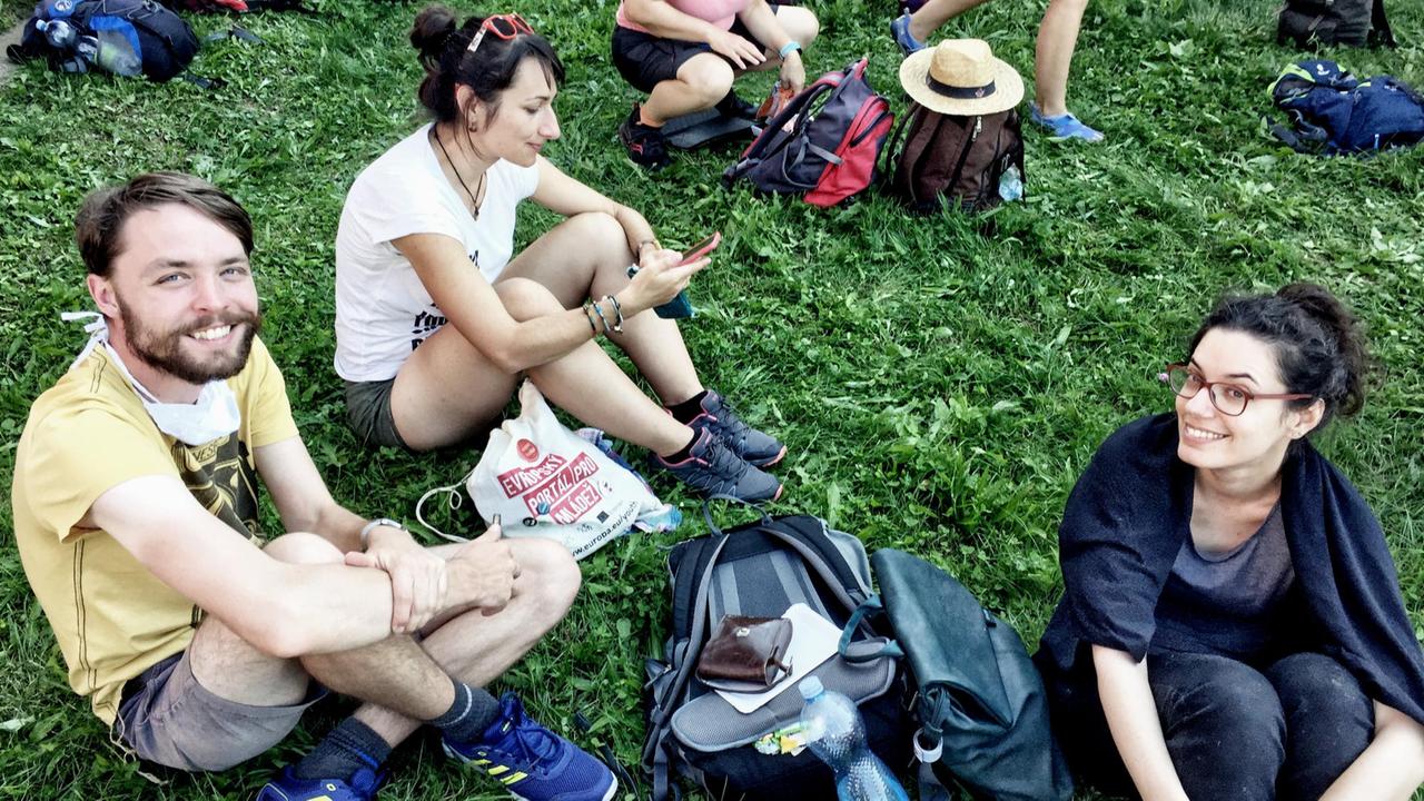Drei junge Menschen sitzen zusammen auf dem Gras Drei junge Menschen sitzen zusammen auf dem Gras