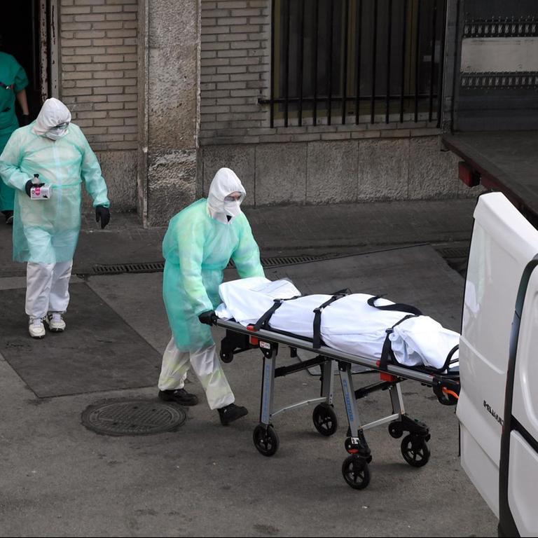 Ein Covid-19-Patient wird in das Gregorio Maranon Krankenhaus in der spanischen Hauptstadt Madrid gebracht. Medizinisches Personal in grüner Schutzkleidung schiebt die Person auf einer Liege.