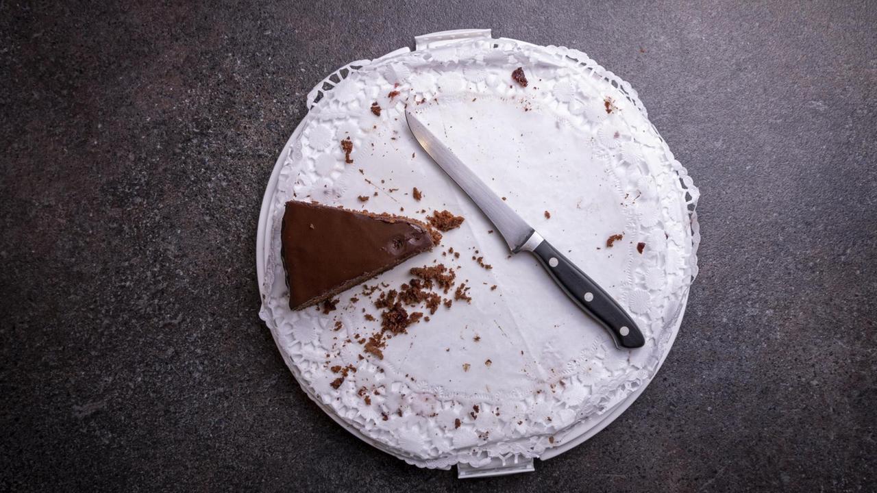 Ein letztes Kuchenstück liegt neben einem Messer auf der Kuchenplatte. Ein letztes Kuchenstück liegt neben einem Messer auf der Kuchenplatte.