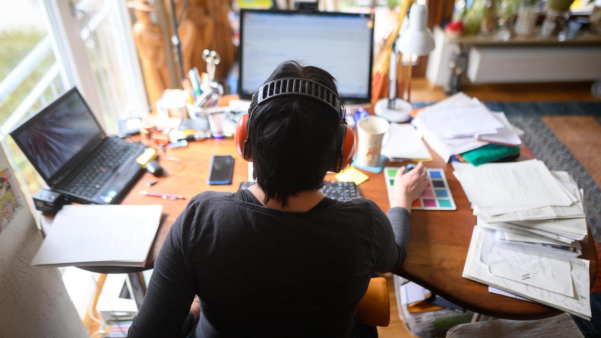 Eine Frau arbeitet im Homeoffice an ihrem Schreibtisch Eine Frau arbeitet im Homeoffice an ihrem Schreibtisch