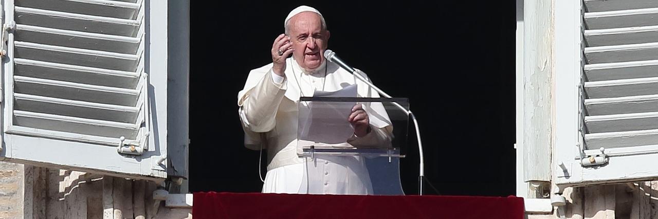 Papst Franziskus während des Angelus-Gebets auf dem Petersplatz. Er steht am offenen Fenster und hebt die rechte Hand (2019). Papst Franziskus während des Angelus-Gebets auf dem Petersplatz. Er steht am offenen Fenster und hebt die rechte Hand (2019).