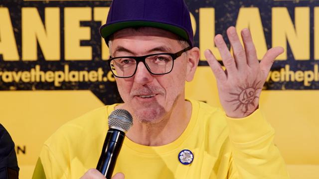 Loveparade-Gründer Dr. Motte stellt bei einer Pressekonferenz in Berlin sein neues Projekt "Rave the Planet" vor. Er trägt einen gelben Pullover und eine dunkelblaue Mütze.