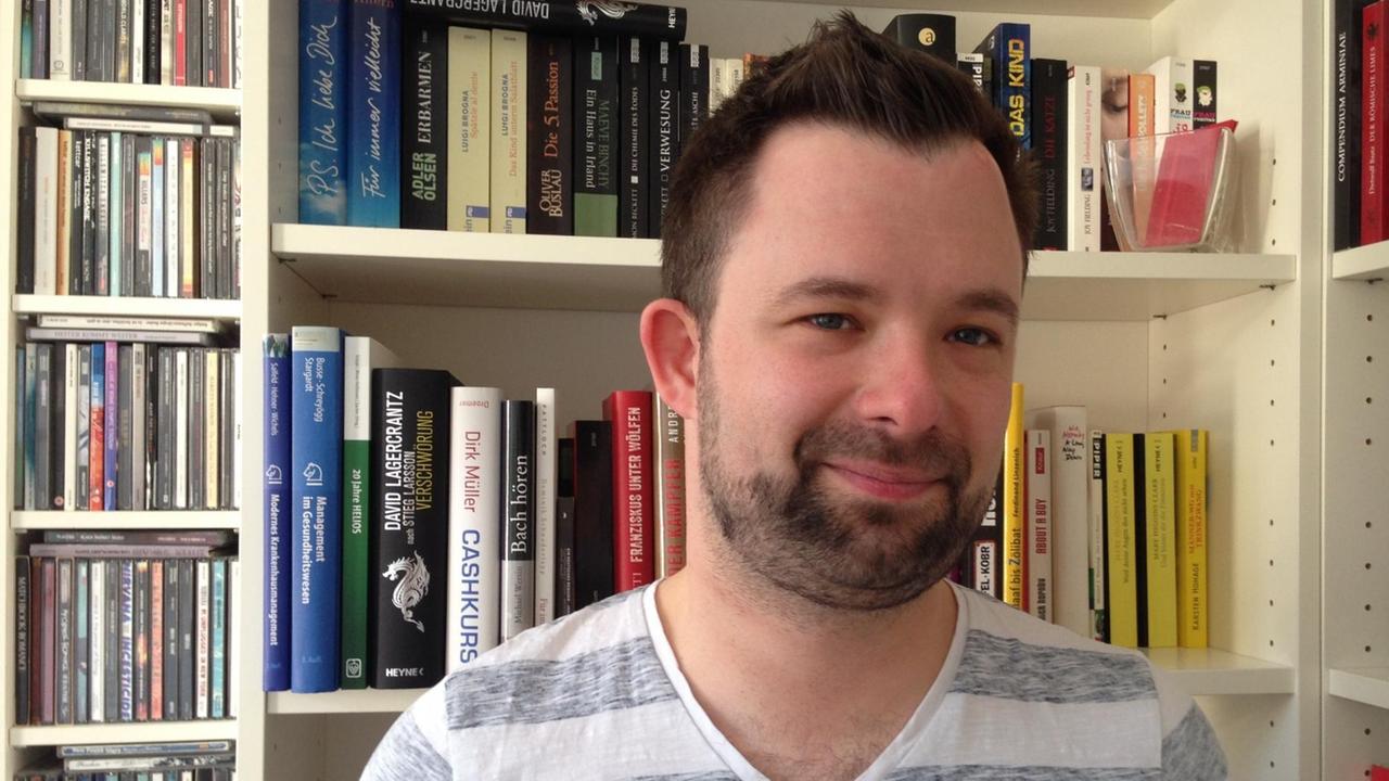 Philipp Heinen steht vor einem Bücherregal. Philipp Heinen steht vor einem Bücherregal.