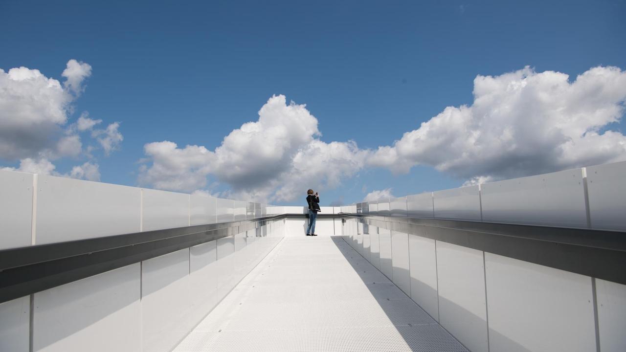 Eine Frau steht bei leicht bewölktem Wetter auf dem "Skywalk" auf dem Dach des "Futurium". Eine Frau steht bei leicht bewölktem Wetter auf dem "Skywalk" auf dem Dach des "Futurium".