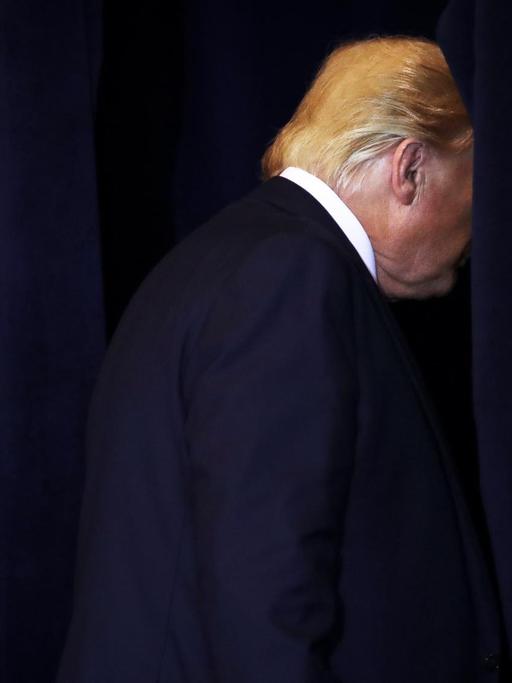 Präsident Trump verlässt den Raum einer Pressekonferenz, nur noch der Hinterkopf ist zu sehen.