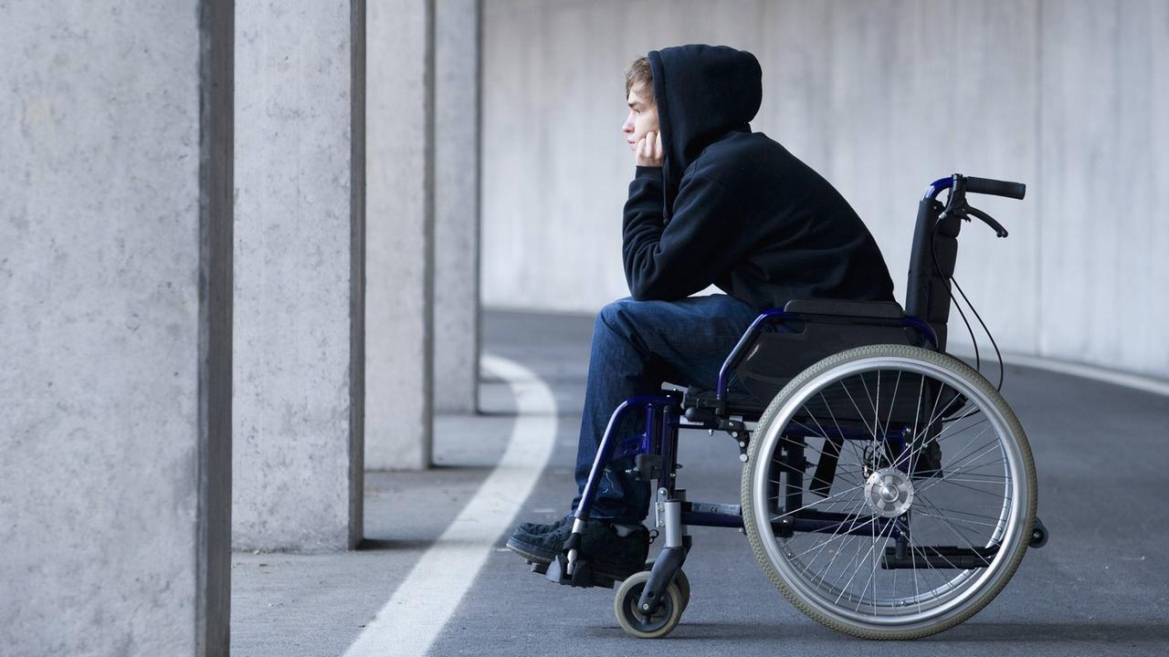 Ein junger Mann sitzt in einem Rollstuhl.