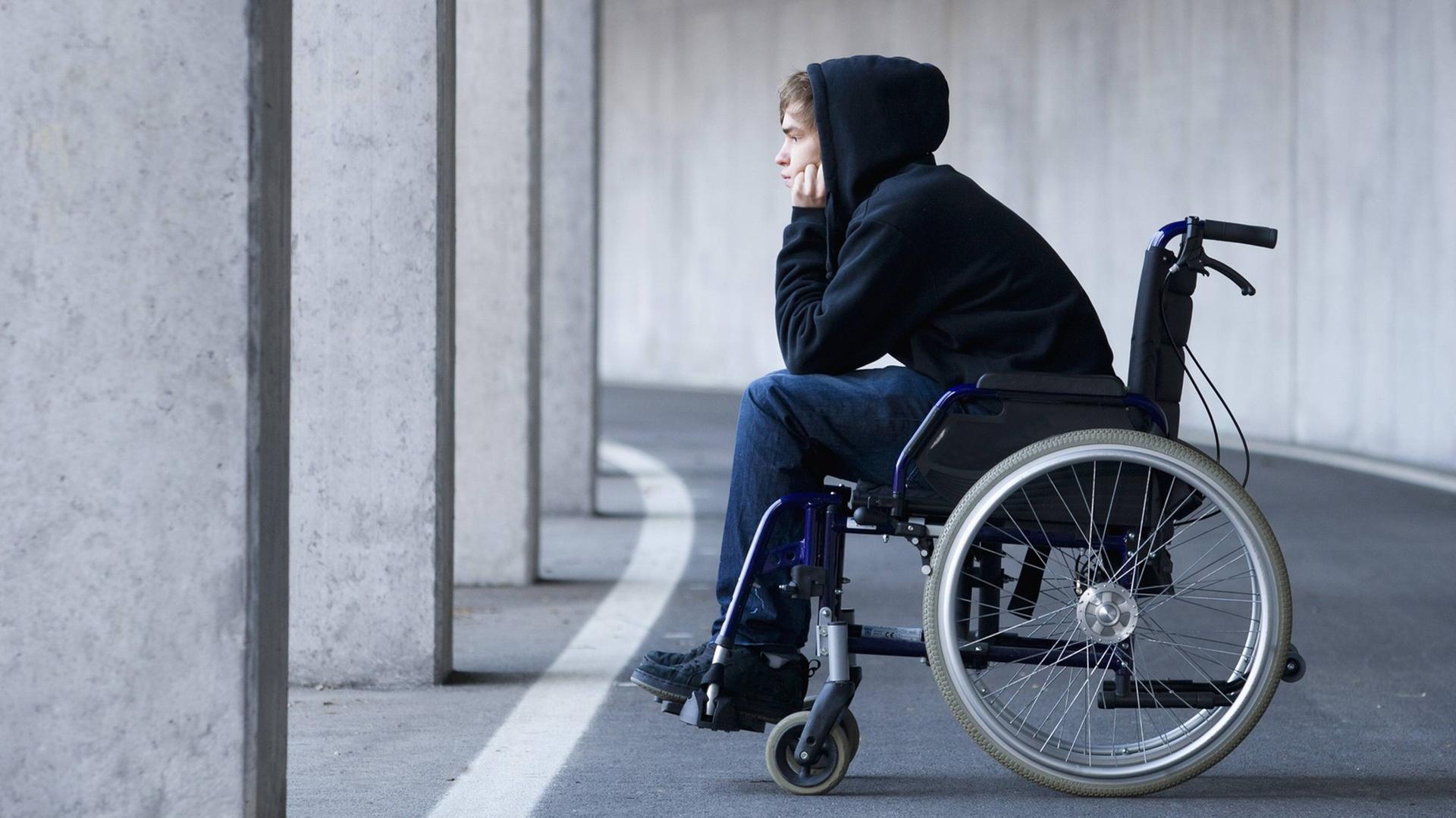 Ein junger Mann sitzt in einem Rollstuhl. Ein junger Mann sitzt in einem Rollstuhl.