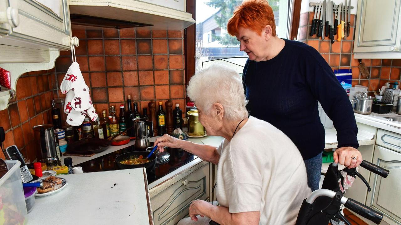 Pflegebedürftige im Rollstuhl in der Küche mit einer Pflegekraft.