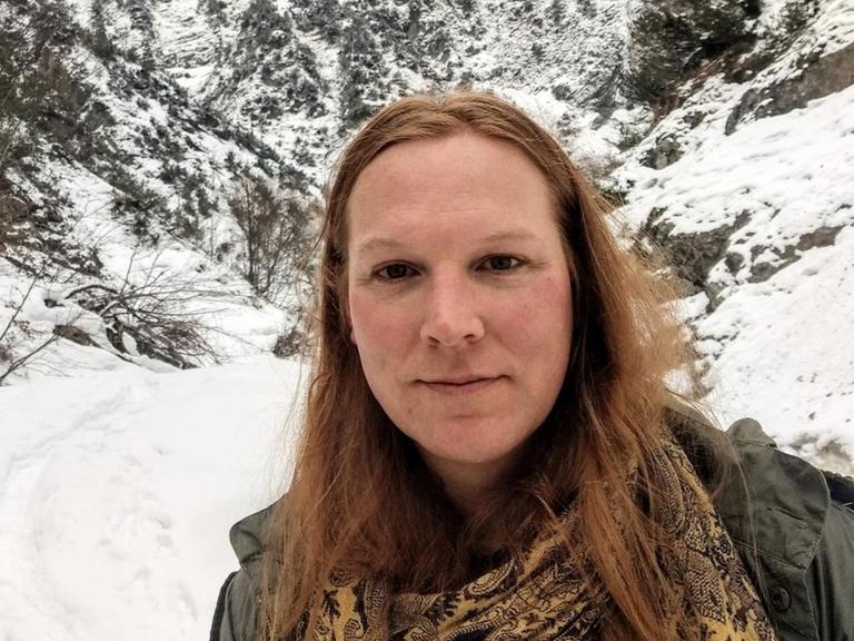 Hannah Aram steht in einem schneebedecktem Tal im Gebirge.